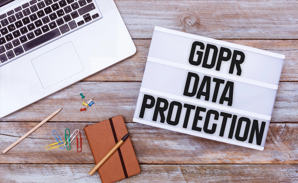 IT-Commander GDPR Data Protection Szene mit Laptop, Notizbuch und Pinnwand-Beschilderung GDPR Data Protection auf Holzschreibtisch, rechtliche Sicherheit