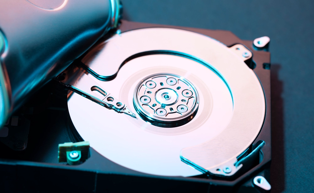 IT Commander Datensicherung: Nahaufnahme einer Festplatte mit blauem Licht und metallischen Drehbausteinen, Visualisierung von Datensicherung und Backup-Prozessen.